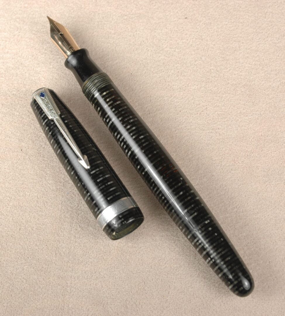 Vintage fountain pen with cap on beige surface.