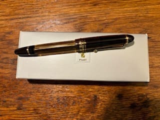 Fountain pen on white box, wooden table.