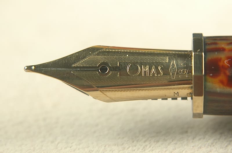 Fountain pen nib close-up, gold and brown.