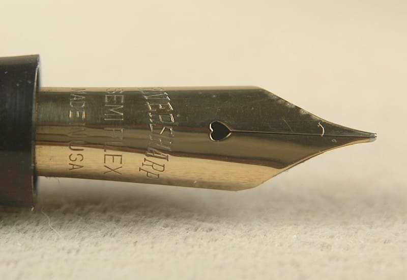 Gold fountain pen nib with heart-shaped hole.