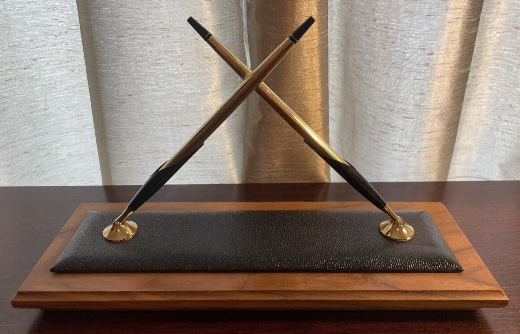 Crossed pens on a wooden display stand.