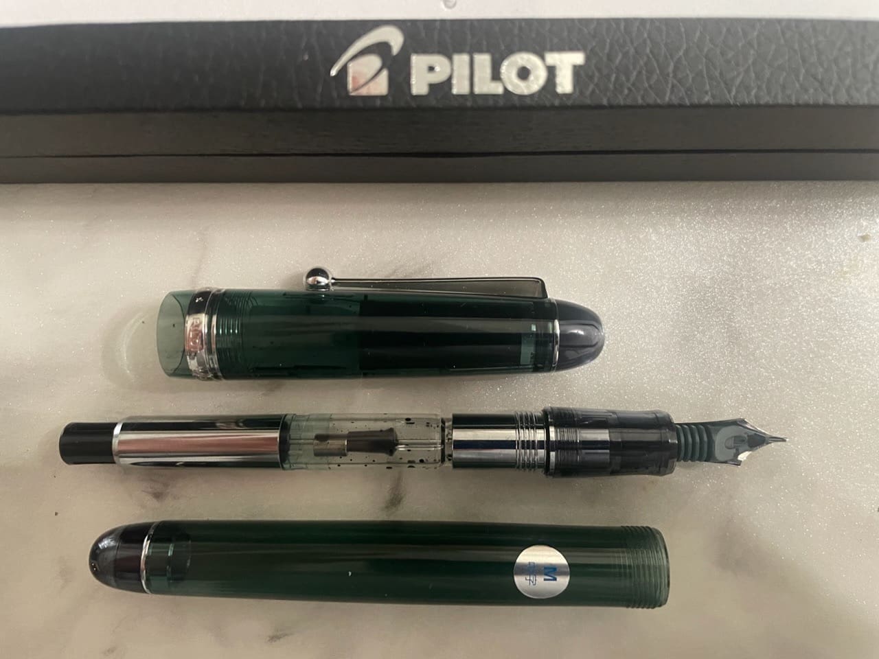 Pilot fountain pen disassembled on white surface.
