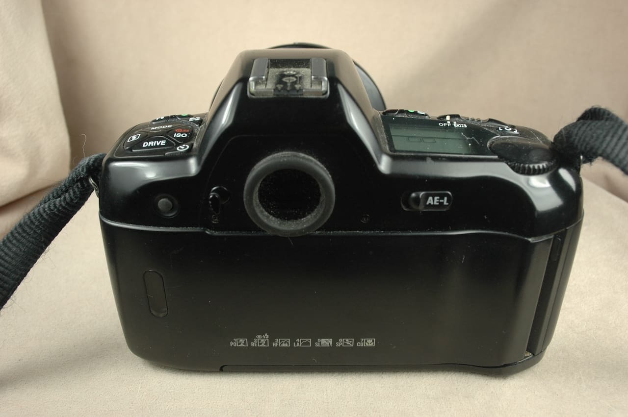 Back view of a vintage Minolta 35mm film camera on a beige surface.