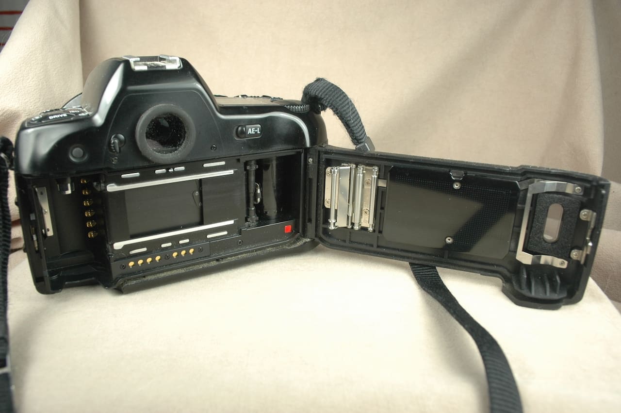 Open vintage film camera showing internal film compartment and controls.