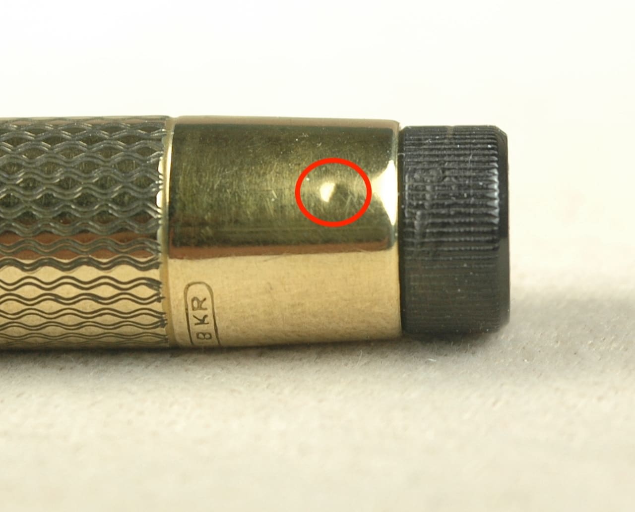 Gold and black pen with red circle.
