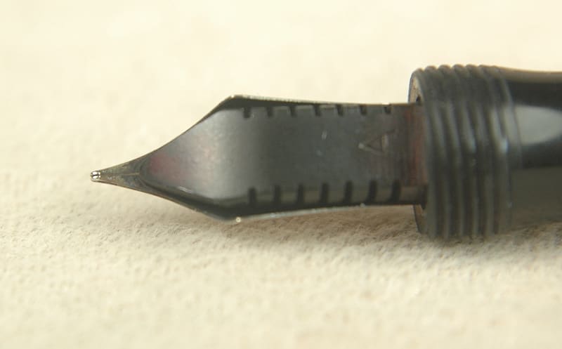 Close-up of a fountain pen nib on a light surface.