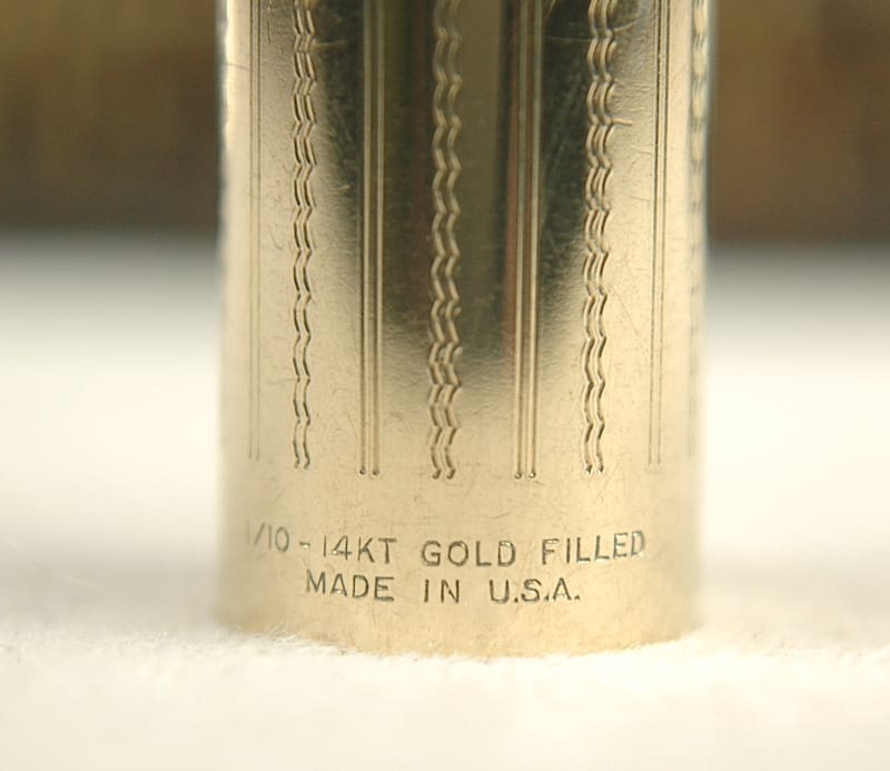 Close-up of a gold-filled metal object with engraved text.