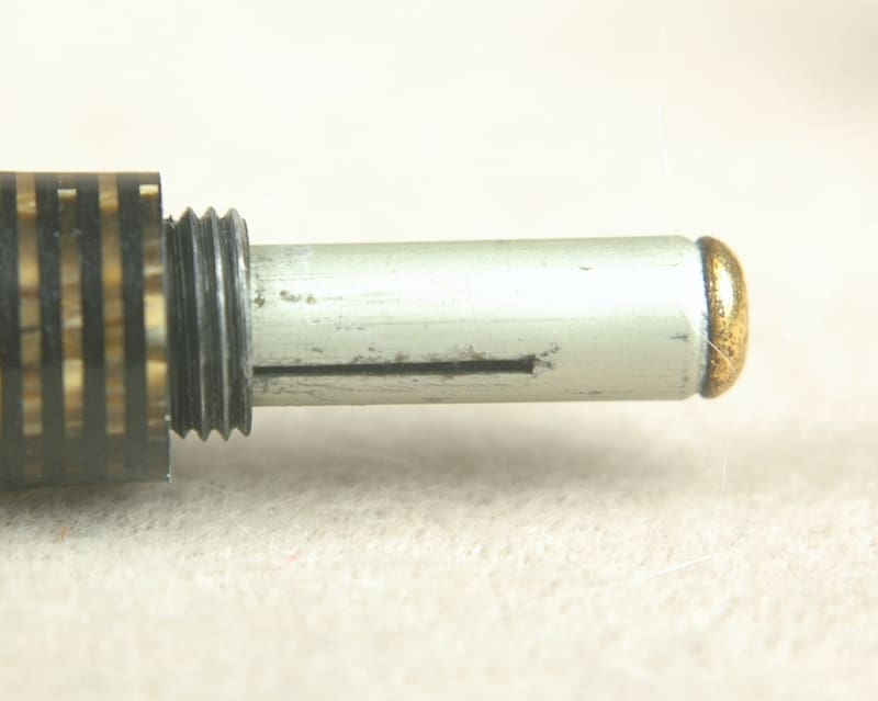Close-up of a metal cylindrical object with threads and a worn tip.