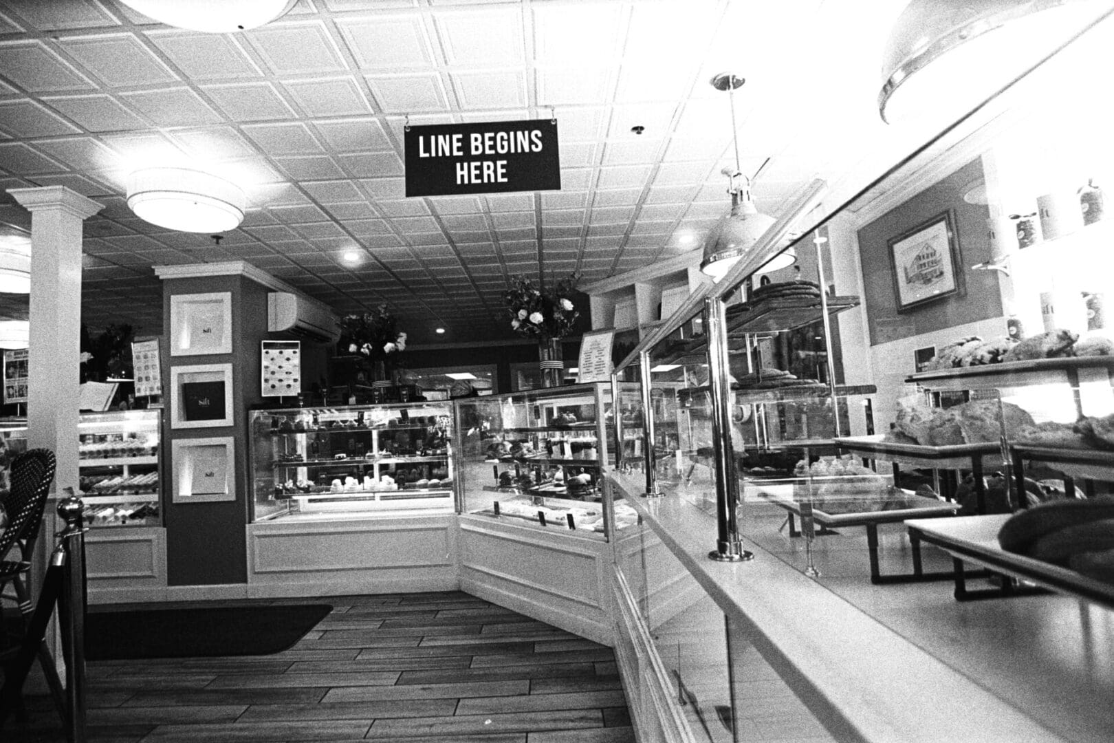 Black and white photo of a vintage bakery interior with a 'Use Beans Here' sign.