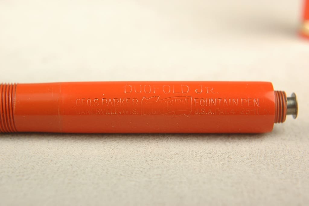 Close-up of an orange pencil with barely visible engraved text.