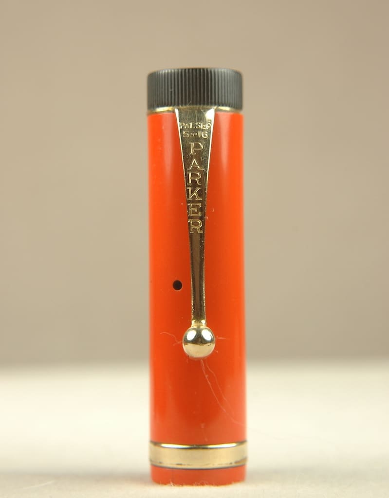 A close-up of an orange lighter with a silver ignition mechanism.