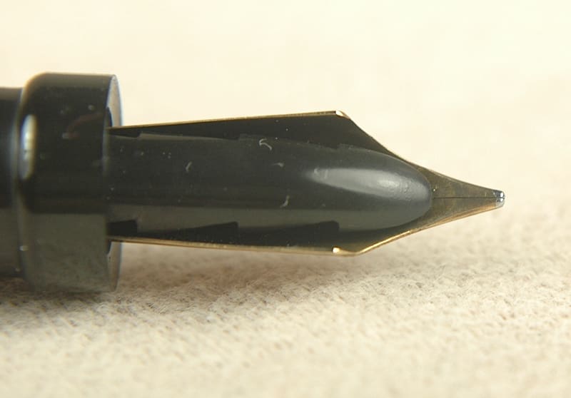 Close-up of a black pen nib on a light surface.
