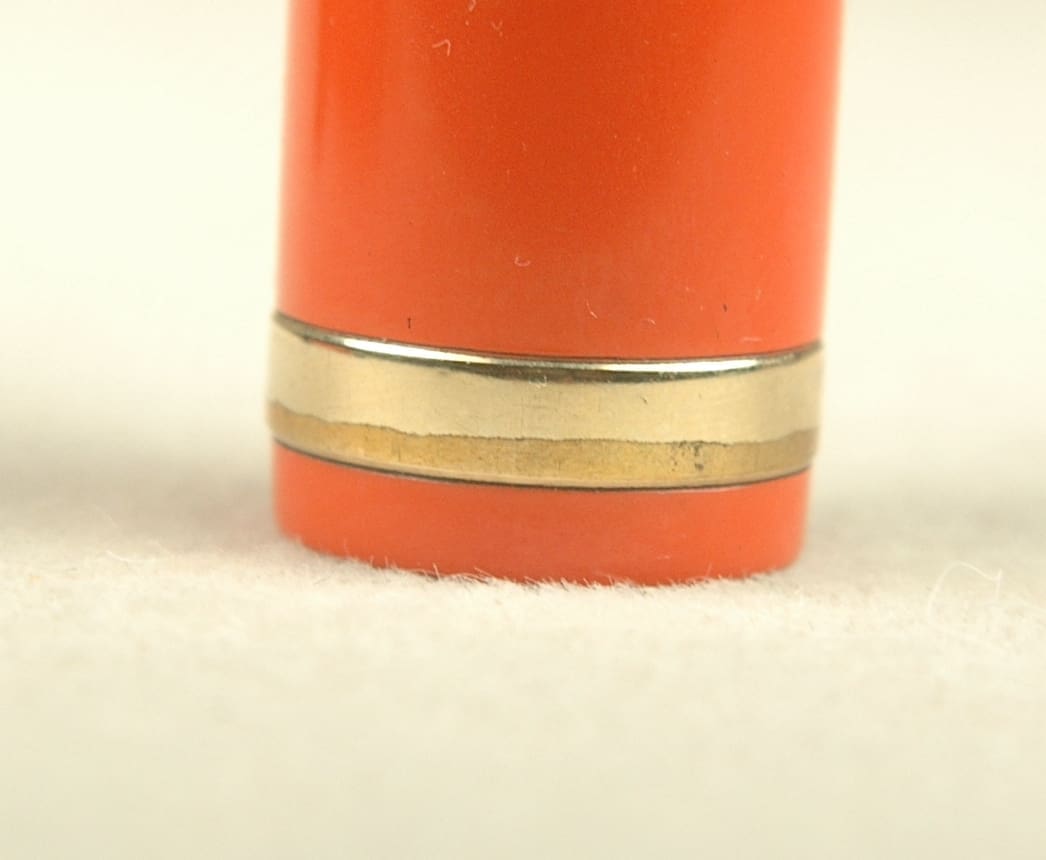 Close-up of an orange lipstick tube with gold accents.