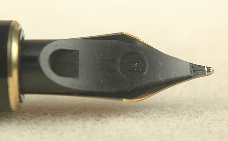 Close-up of a black fountain pen nib tip on a light surface.