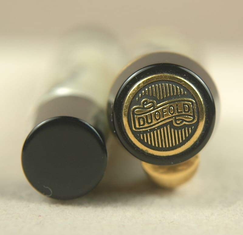 Close-up of a fountain pen nib and cap on a white surface.