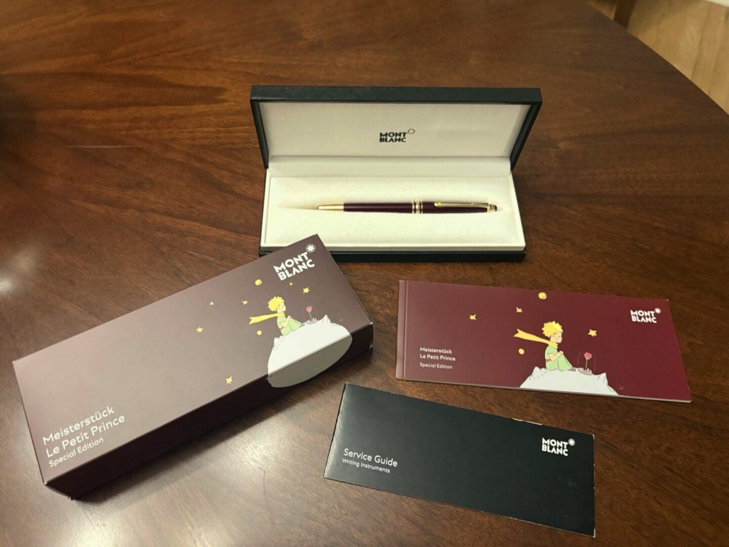 Elegant Montblanc pen with packaging and booklet on wooden surface.