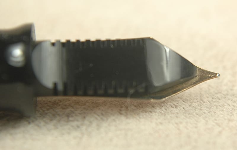 Close-up of a serrated knife blade on a textured surface.