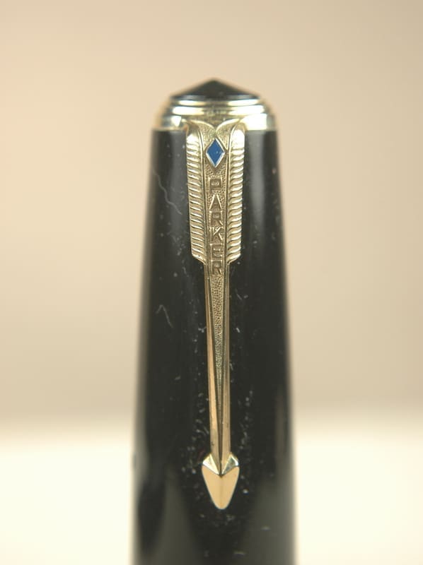 Close-up of a black pen with a gold arrow-shaped clip.