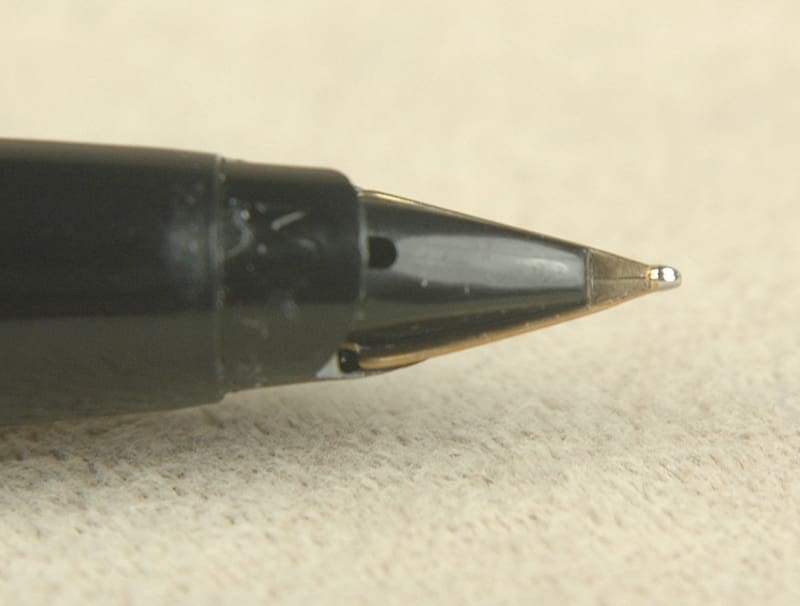Close-up of a black pen tip on textured paper.