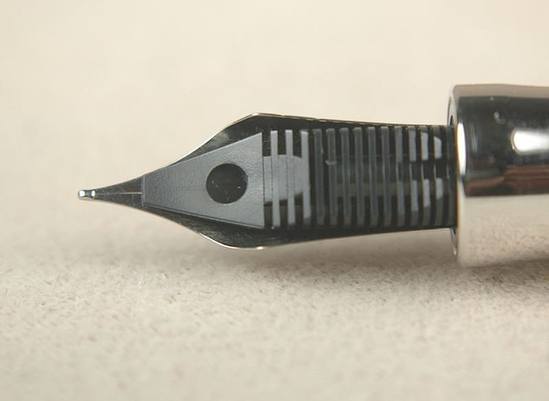 Close-up of a fountain pen nib on a beige surface.