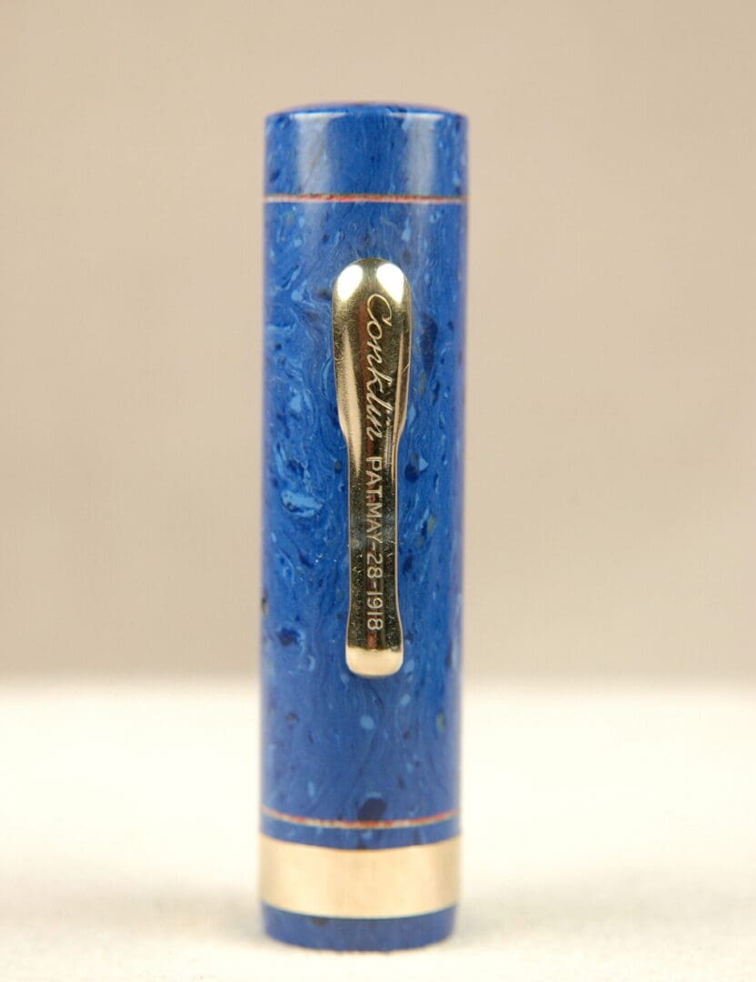 Close-up of a blue fountain pen cap with a gold clip and intricate texture.