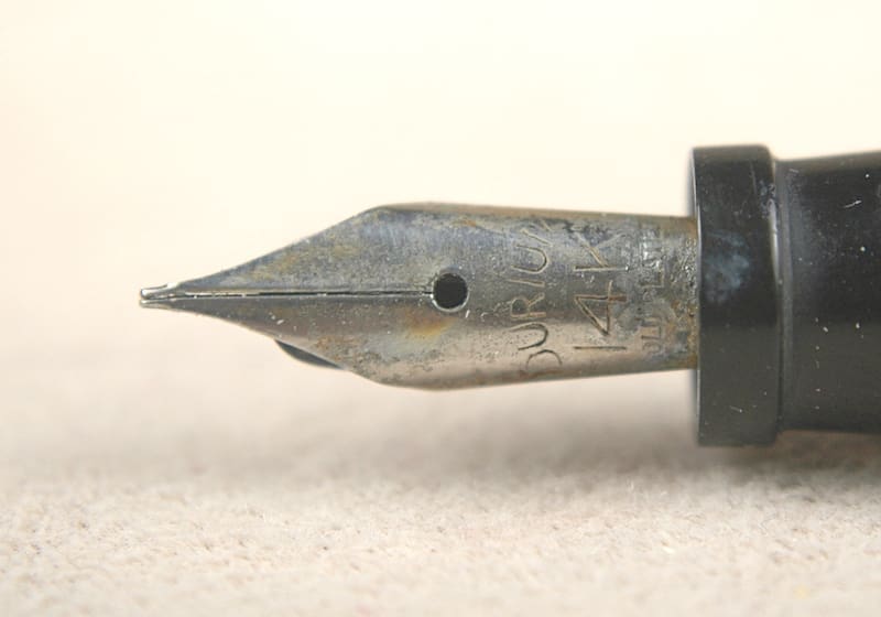 Close-up of a worn fountain pen nib with ink residue.