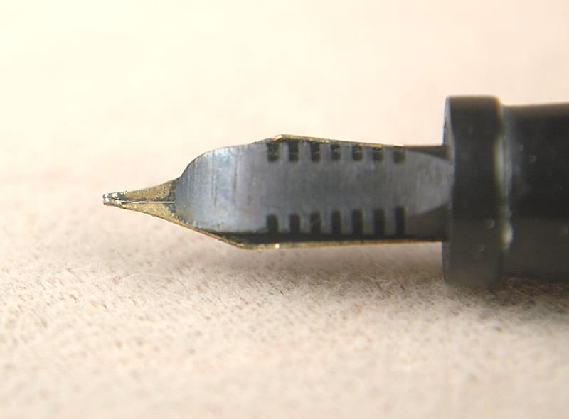Close-up of a fountain pen nib on a light surface.