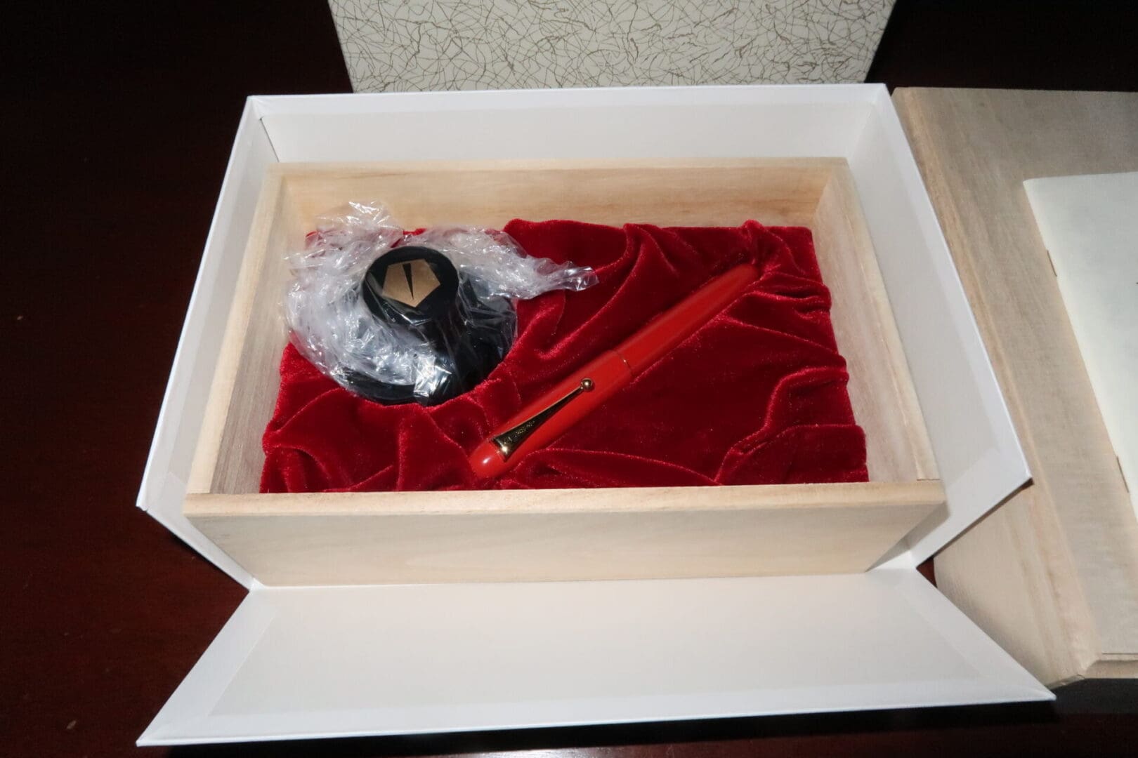 A decorative box with a small doll on red velvet inside.