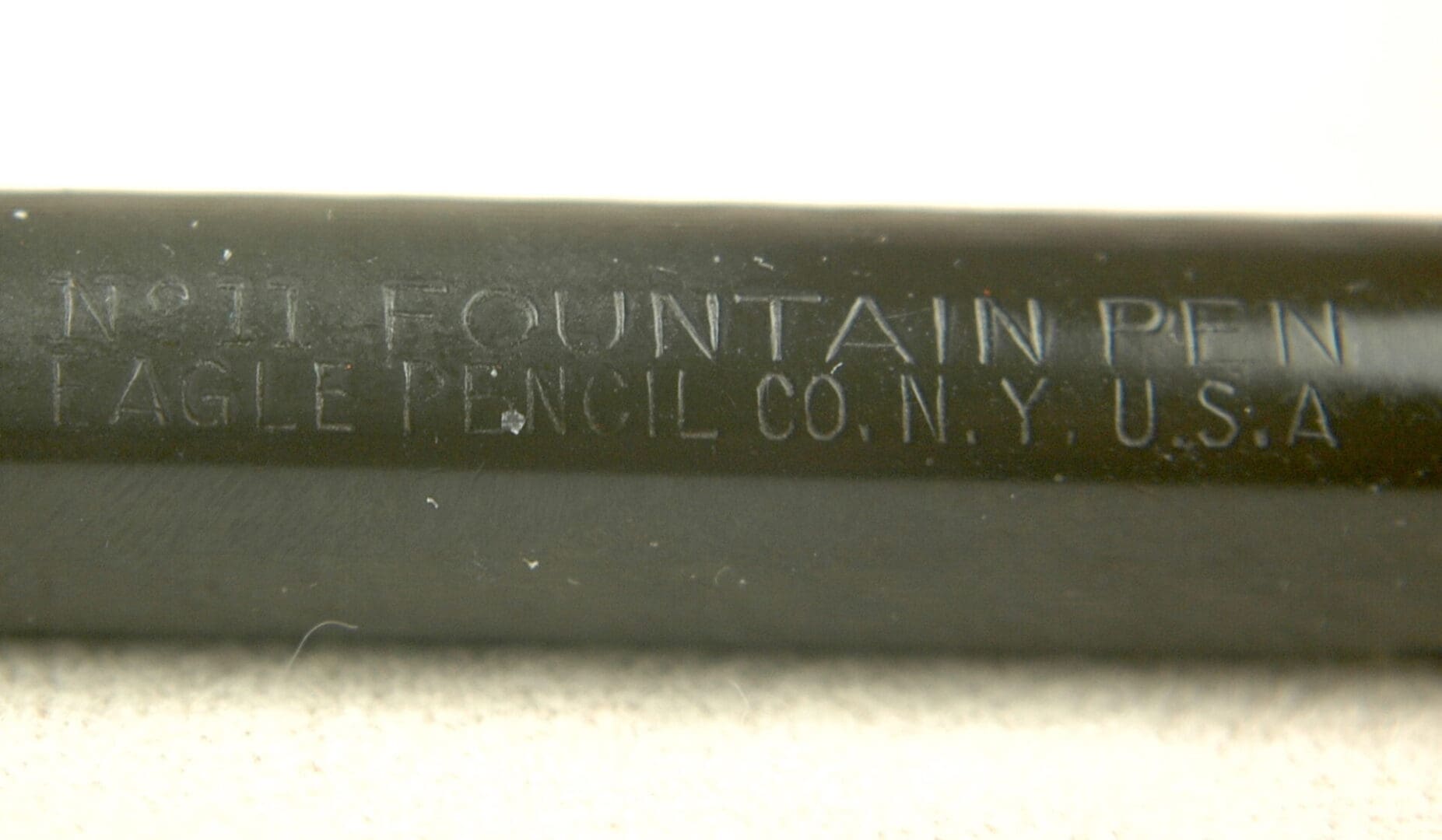 Close-up of a metal object engraved with 'FOUNTAIN PENCIL CO. N.Y.'