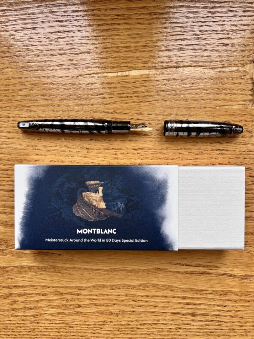 Montblanc pens displayed with their box on a wooden surface.