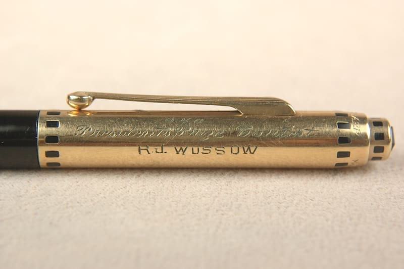 Close-up of a gold pen with "R.O. VISSER" engraved.
