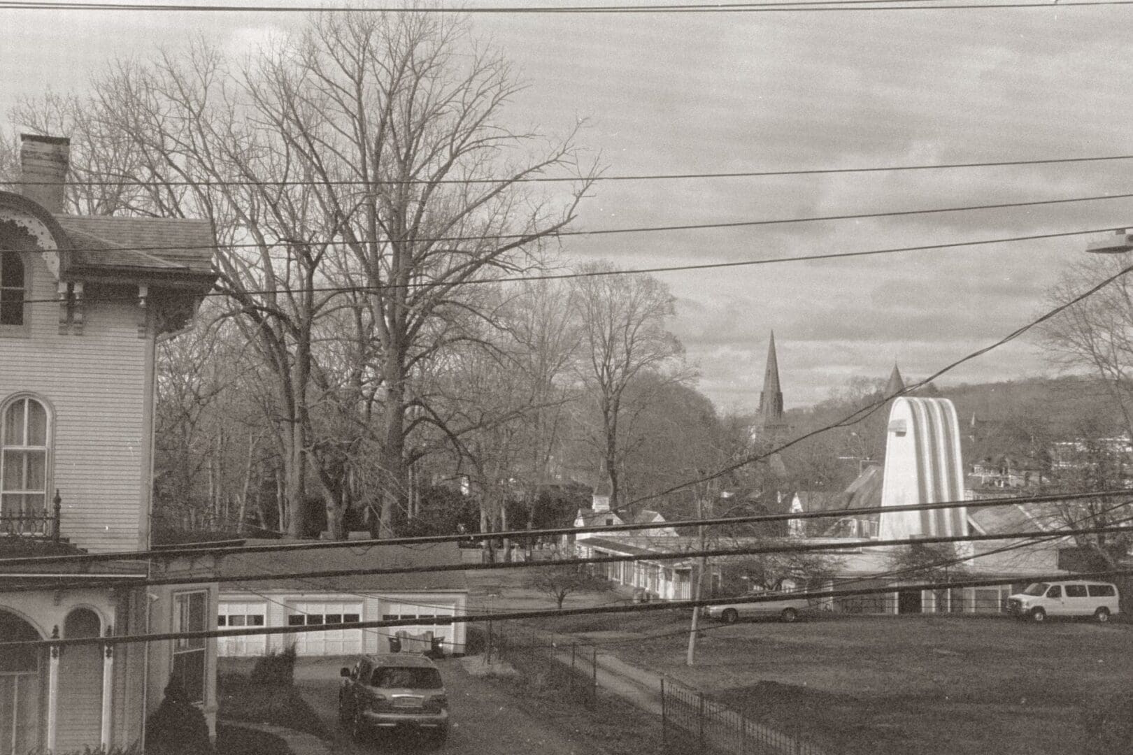 A sepia-toned urban scene with bare trees and rooftops.