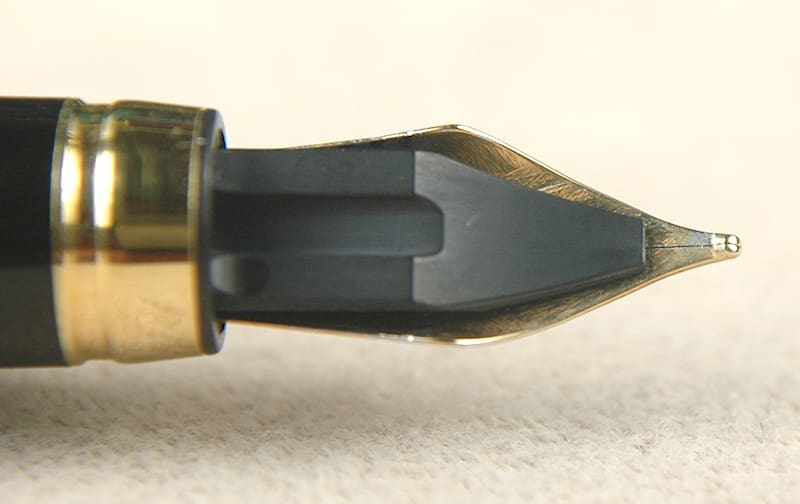 Close-up of a fountain pen nib on a light surface.