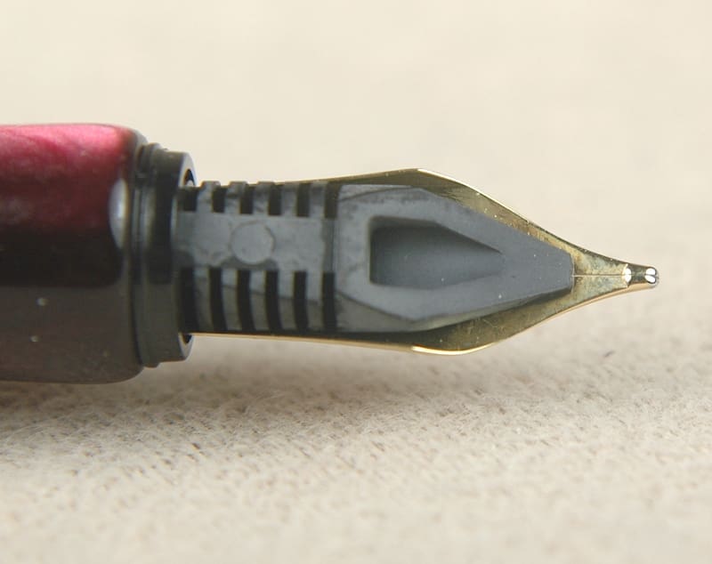 Close-up of a fountain pen nib with a red grip.