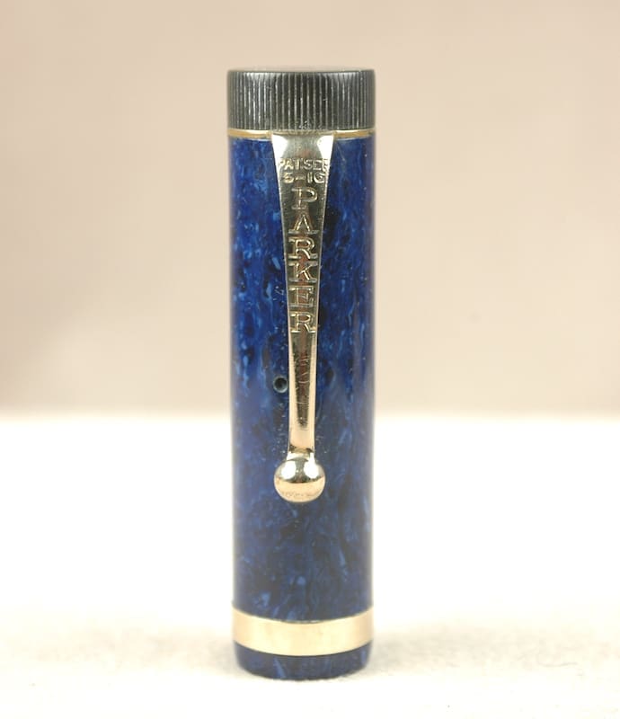 Close-up of a blue pen cap with a silver clip and tip.
