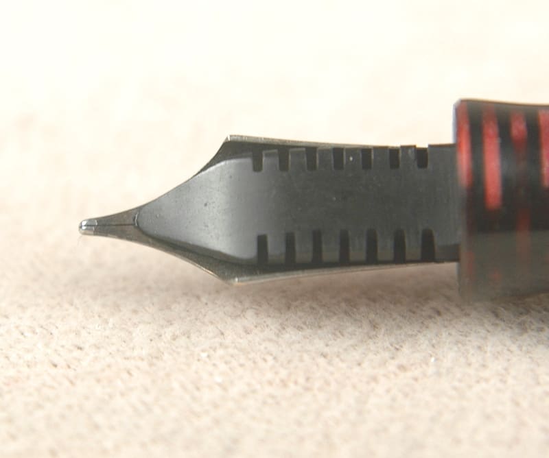 Close-up of a fountain pen nib on a light surface.