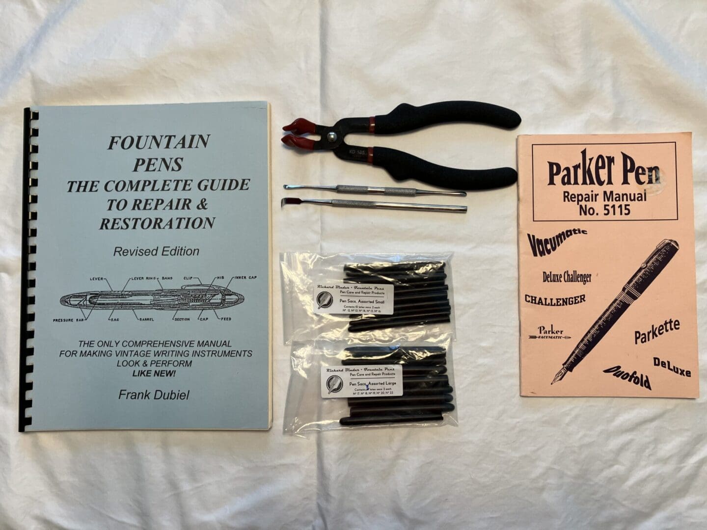 Tools and manuals for fountain pen repair and maintenance laid out on a white surface.